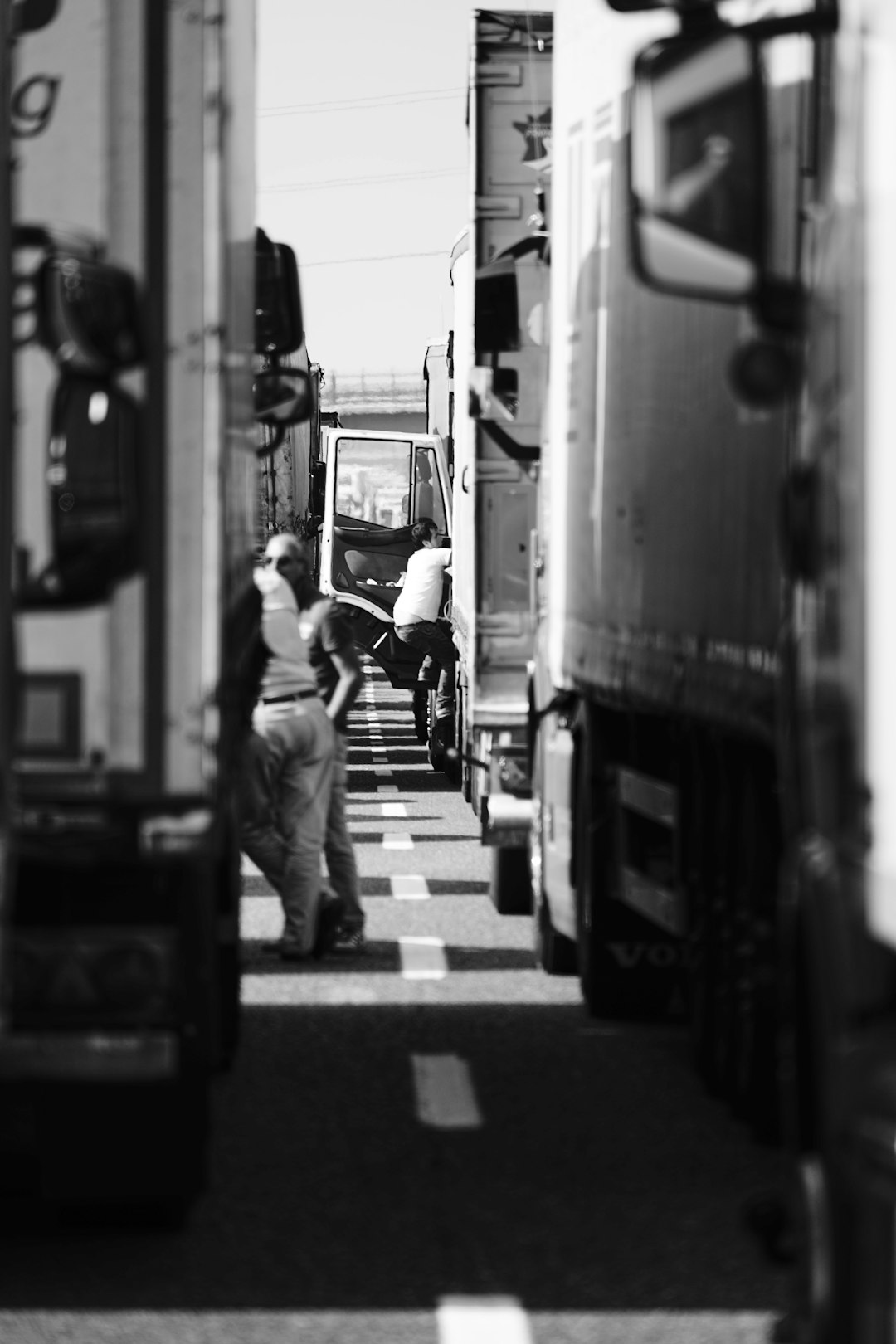 grayscale photo of man walking on pedestrian lane