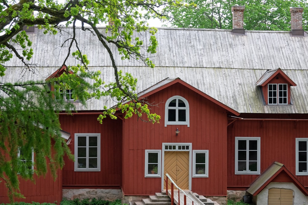 casa de madeira vermelha e branca perto da árvore nua durante o dia