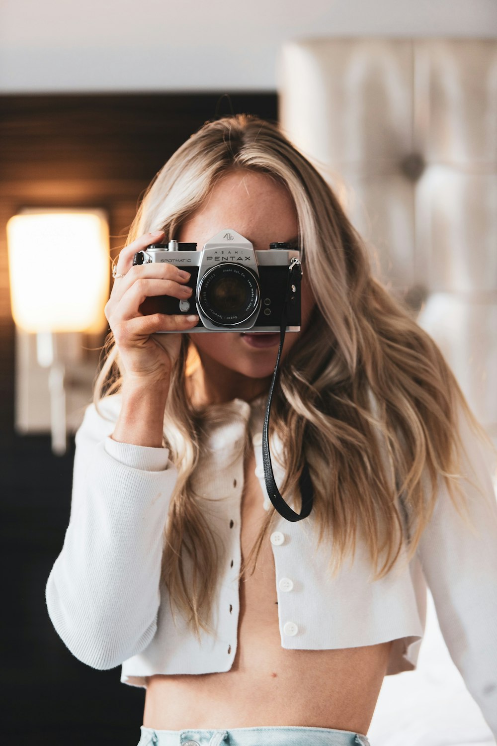 woman in white long sleeve shirt holding black and silver camera