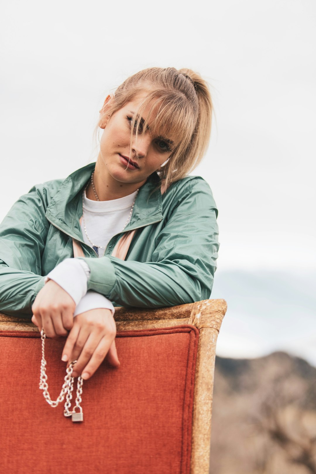 girl in green zip up jacket sitting on brown wooden chair