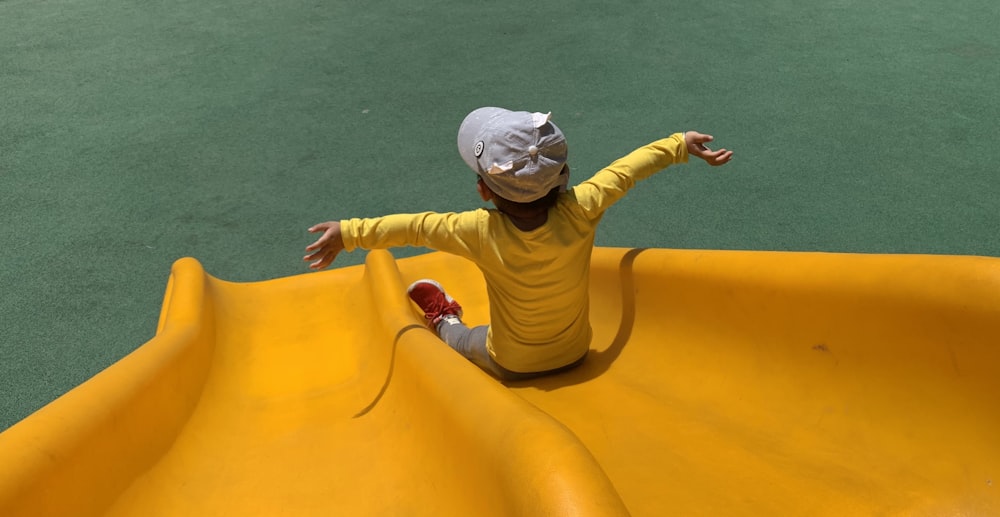 girl in pink and brown long sleeve shirt and pink pants sitting on yellow inflatable ring