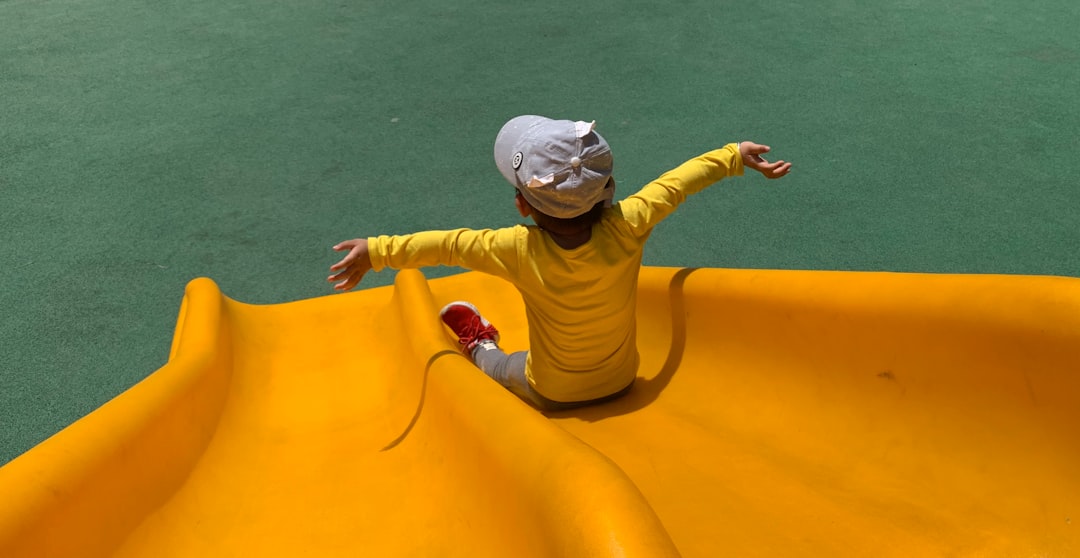 girl in pink and brown long sleeve shirt and pink pants sitting on yellow inflatable ring