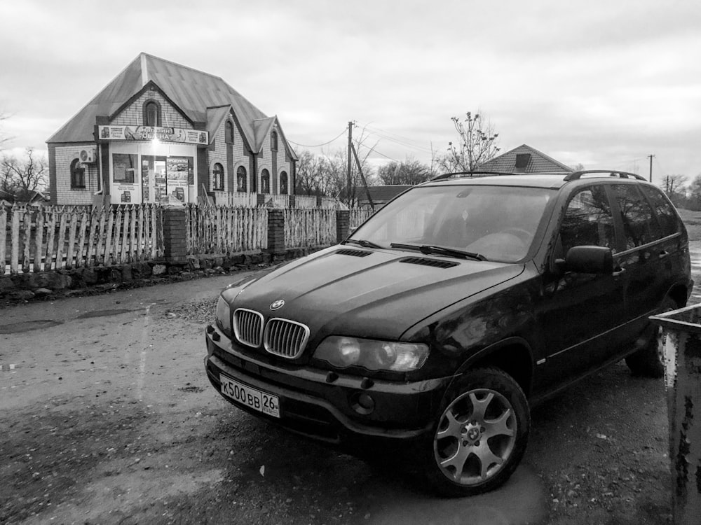 grayscale photo of black bmw x 6 sedan parked near building