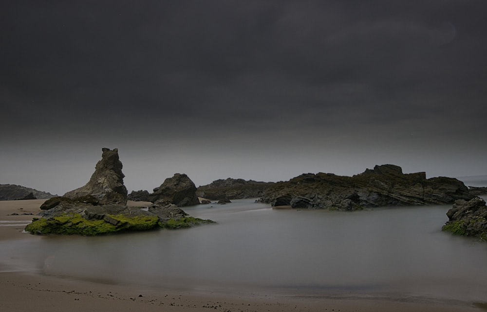 brown rock formation on sea shore under gray sky