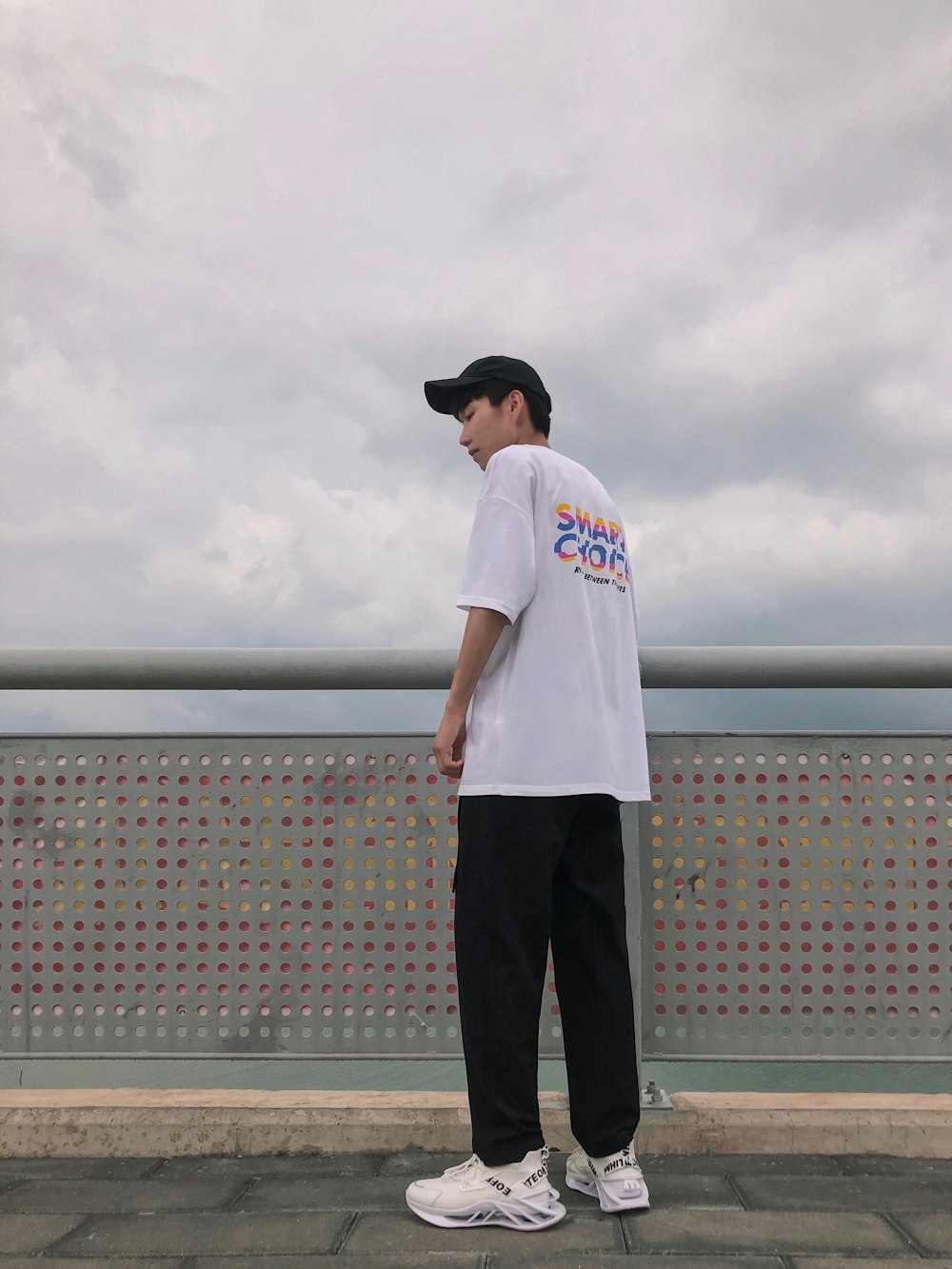 man in white crew neck t-shirt and black pants standing on gray concrete floor during