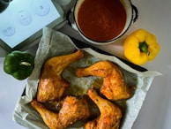 A steaming basket of hot chicken drumsticks, sprinkled with chili flakes and fresh parsley.