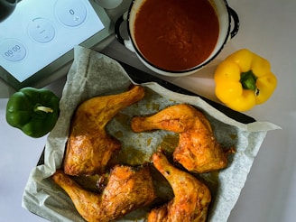 A steaming basket of hot chicken drumsticks, sprinkled with chili flakes and fresh parsley.