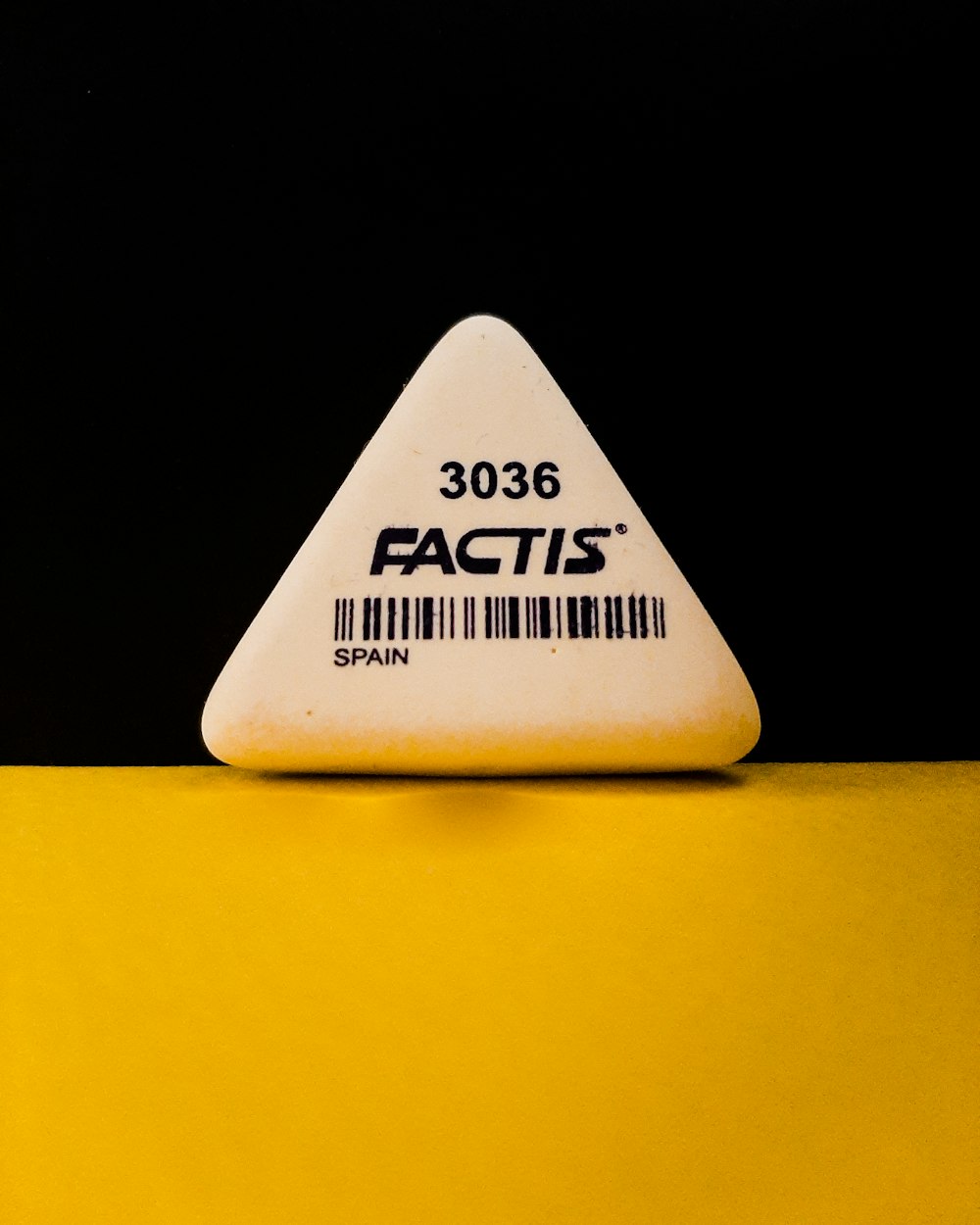 a white triangle shaped object sitting on top of a yellow table