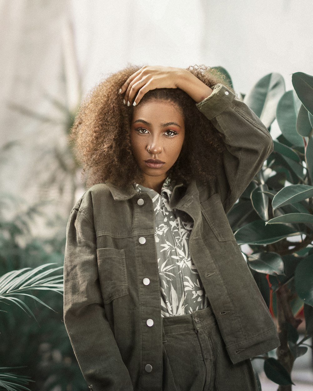 femme en manteau noir debout près de la plante verte pendant la journée