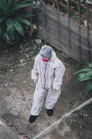 person in white jacket and pants standing near green plant during daytime