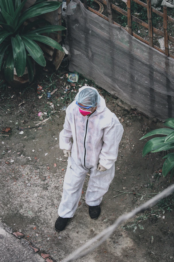 person in white jacket and pants standing near green plant during daytime