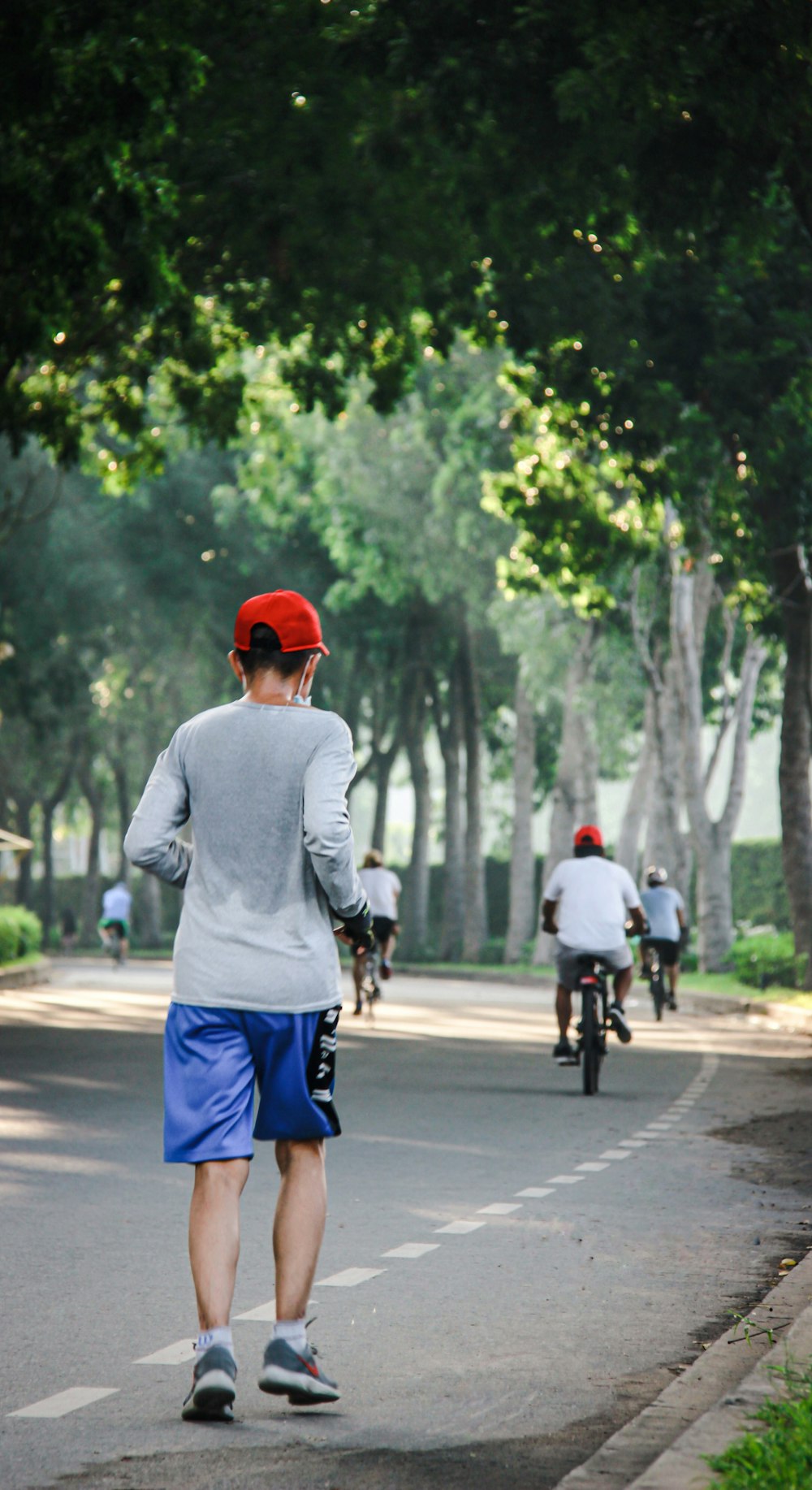 man in gray sweater and blue shorts riding bicycle on road during daytime