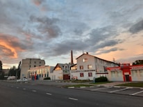 Close-up of a gas meter with industrial buildings in the background during sunset.