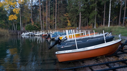 people riding on orange and black boat on river during daytime in Parainen Finland