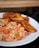 A white plate holds a serving of fried plantains accompanied by a colorful scrambled eggs mixture that includes chopped green peppers, tomatoes, and onions.