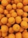 A pile of fresh oranges with a smooth texture and vibrant color, closely packed together. The surface of each orange displays slight variations with small dimples and natural imperfections.