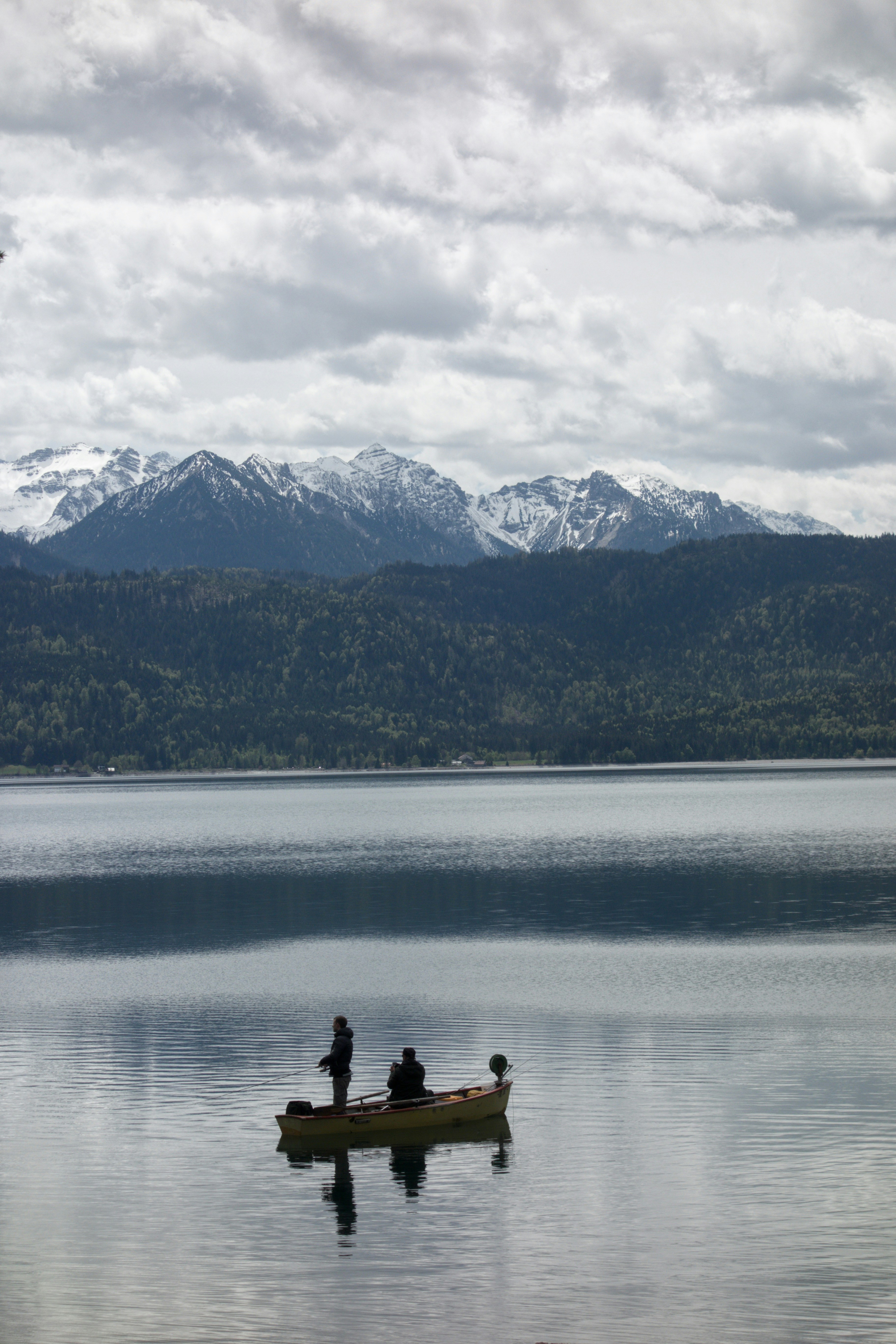 2 person sitting on rock near body of water during daytime
