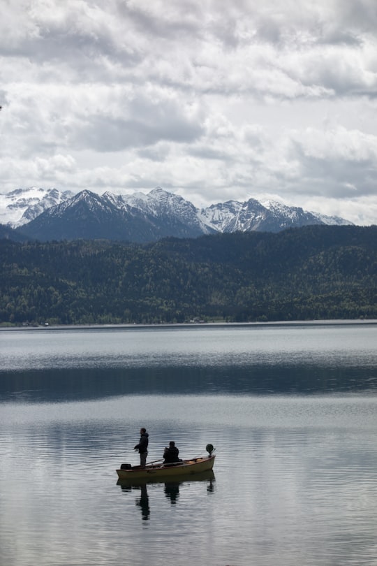 2 person sitting on rock near body of water during daytime in Walchensee Germany