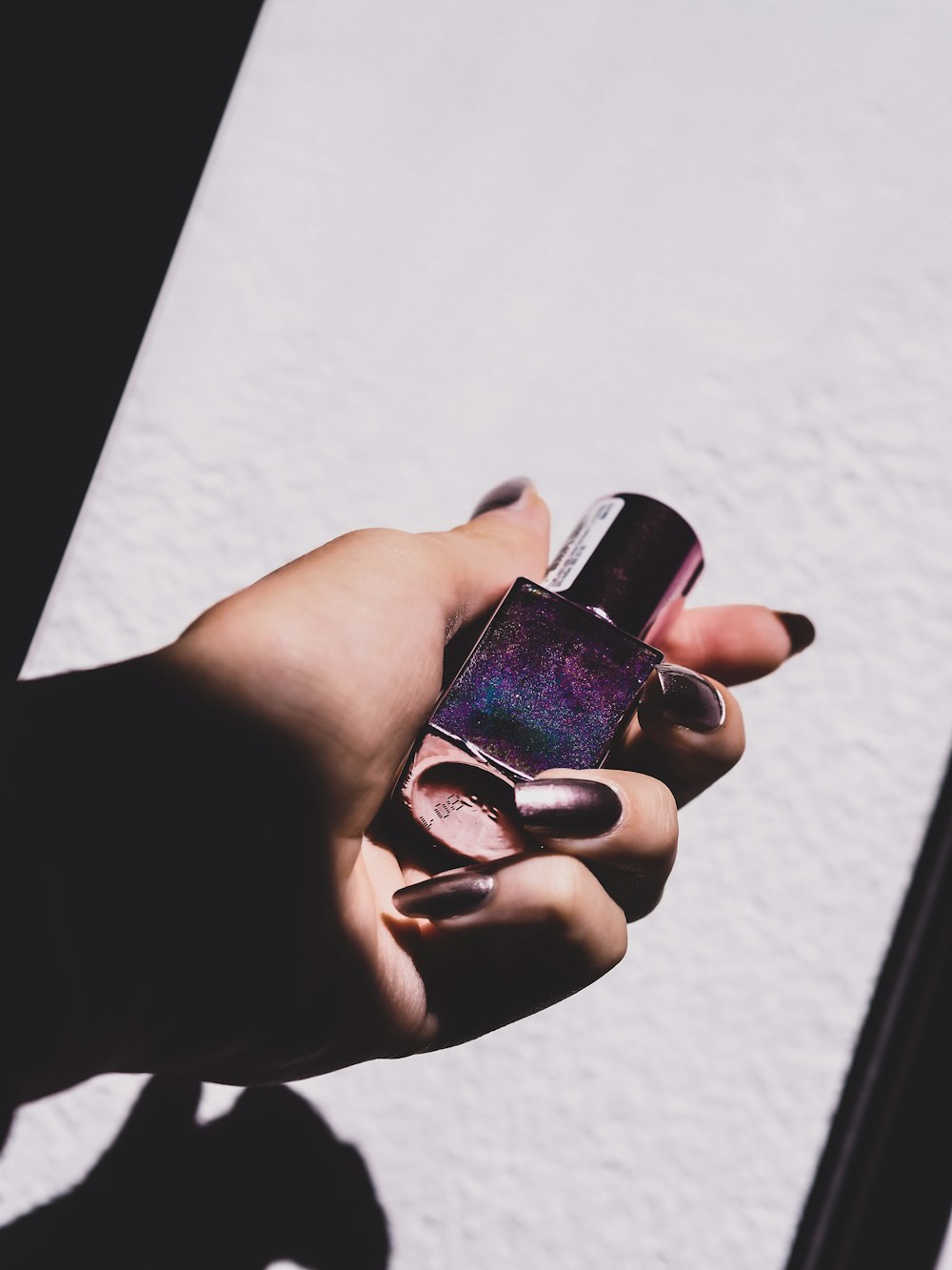 Esmalte de uñas púrpura en la mano de las personas