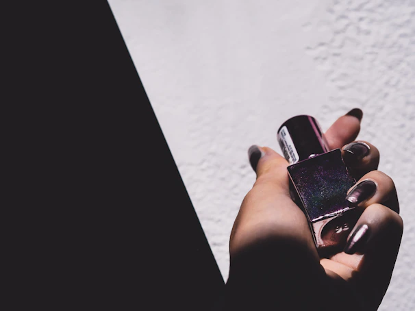 Minimalist flat lay of premium nail glue bottle and applicator on a white background with subtle shadows.