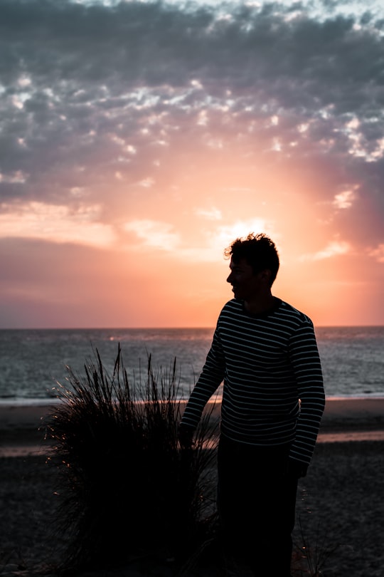 man in black and white striped long sleeve shirt standing near sea during sunset in Côte Sauvage France