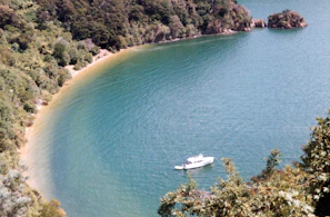 A serene turquoise bay on a secluded island with a small wooden boat anchored near the shore.