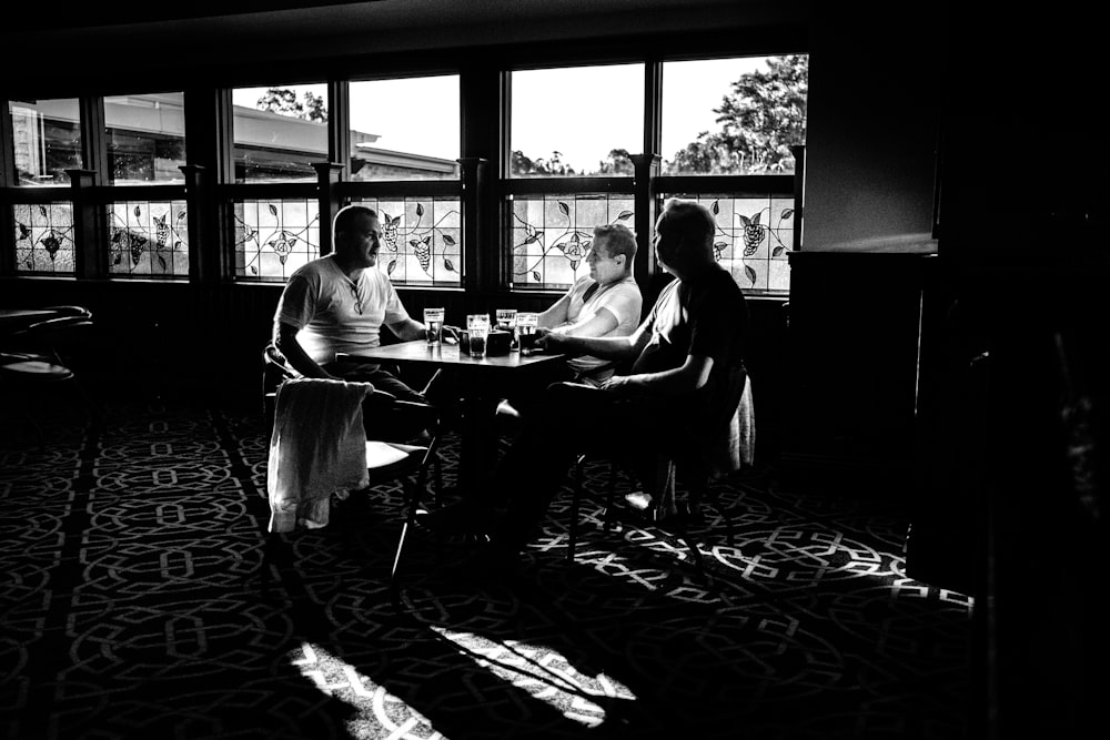 2 men sitting on chair in grayscale photography