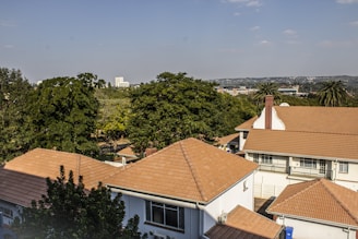 brown and white concrete house near green trees under blue sky during daytime