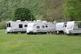 white and brown rv trailer on green grass field during daytime
