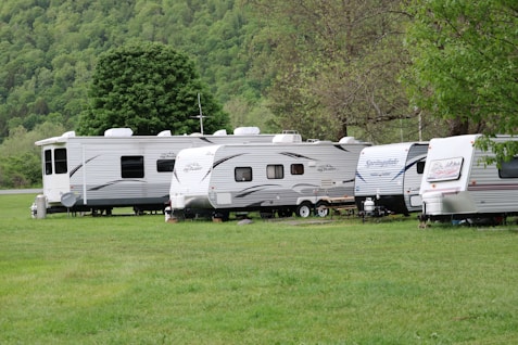 white and brown rv trailer on green grass field during daytime