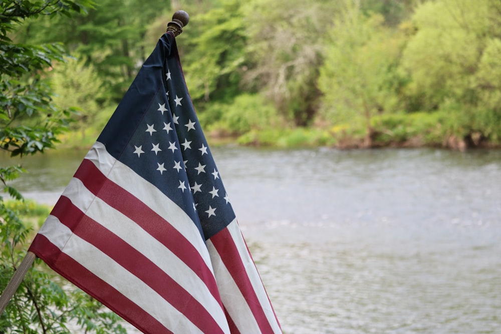日中の水域近くのポールに旗を立てる米国