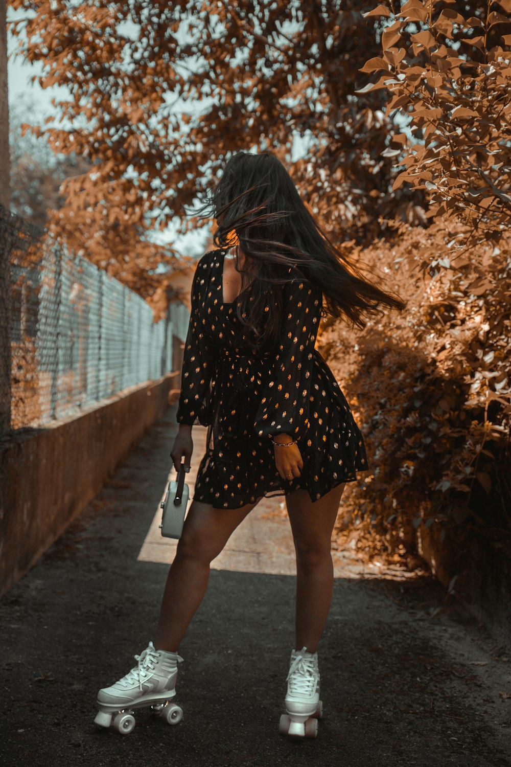 woman in black and white polka dot dress walking on pathway