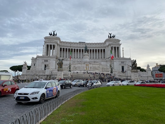 cars parked in front of white concrete building during daytime in Piazza Venezia Italy