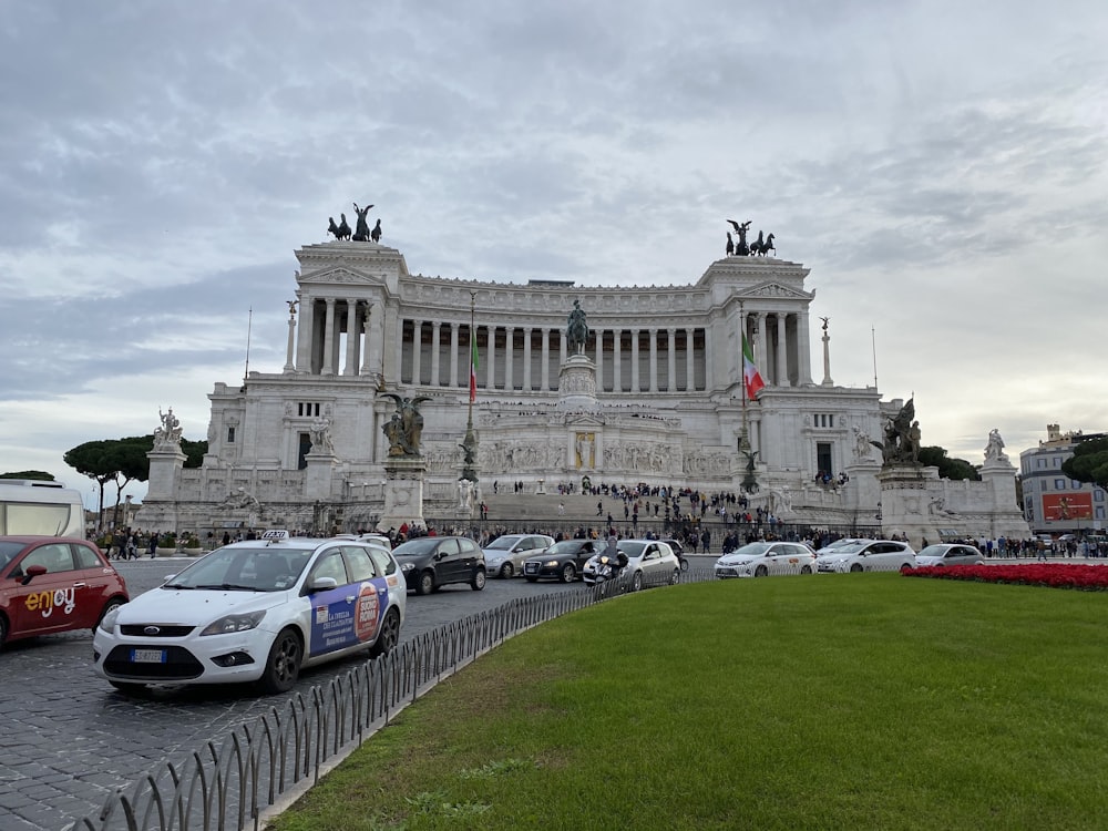 auto parcheggiate davanti all'edificio in cemento bianco durante il giorno