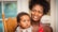 A mother smiling while holding her baby in a cozy living room.