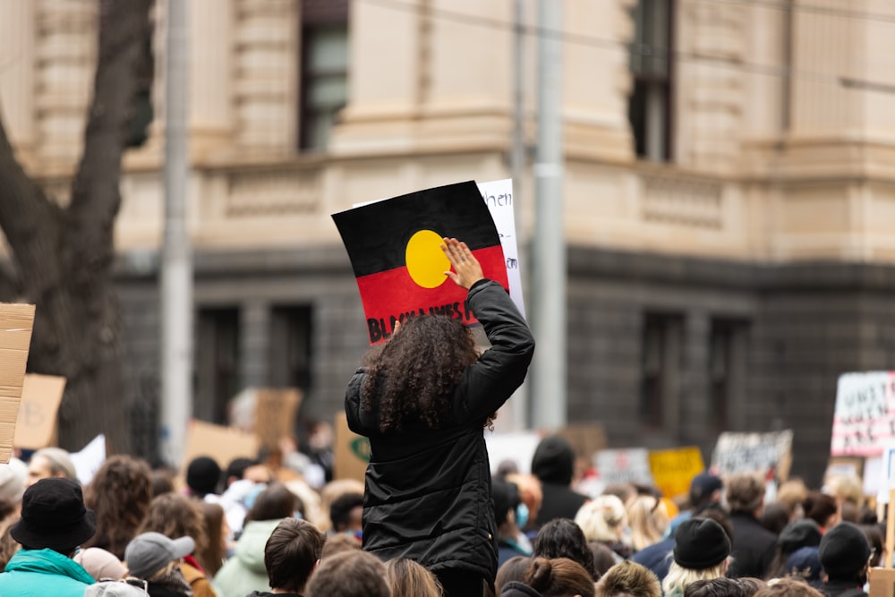 man in black jacket holding red and yellow flag