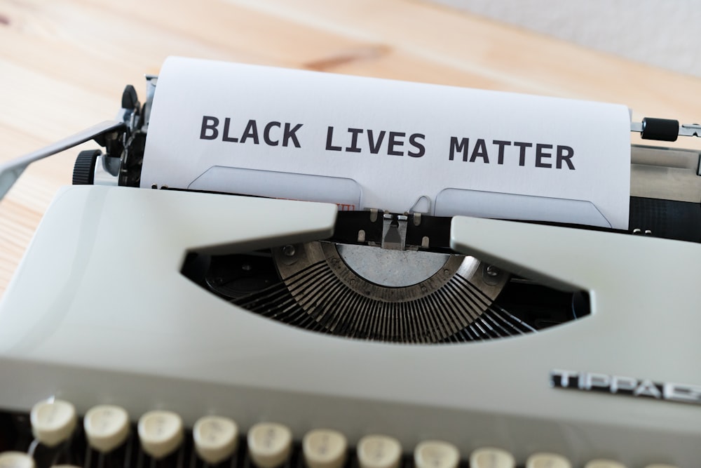 a close up of a typewriter with a paper that reads black lives matter