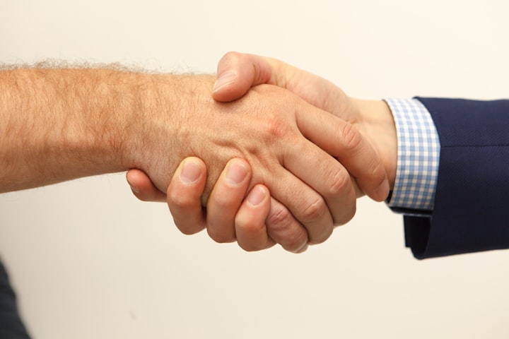 two guys handshaking, one with suit one in business casual 