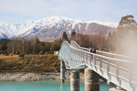 woman in black jacket standing on white bridge over river during daytime in Peppers Bluewater Resort New Zealand