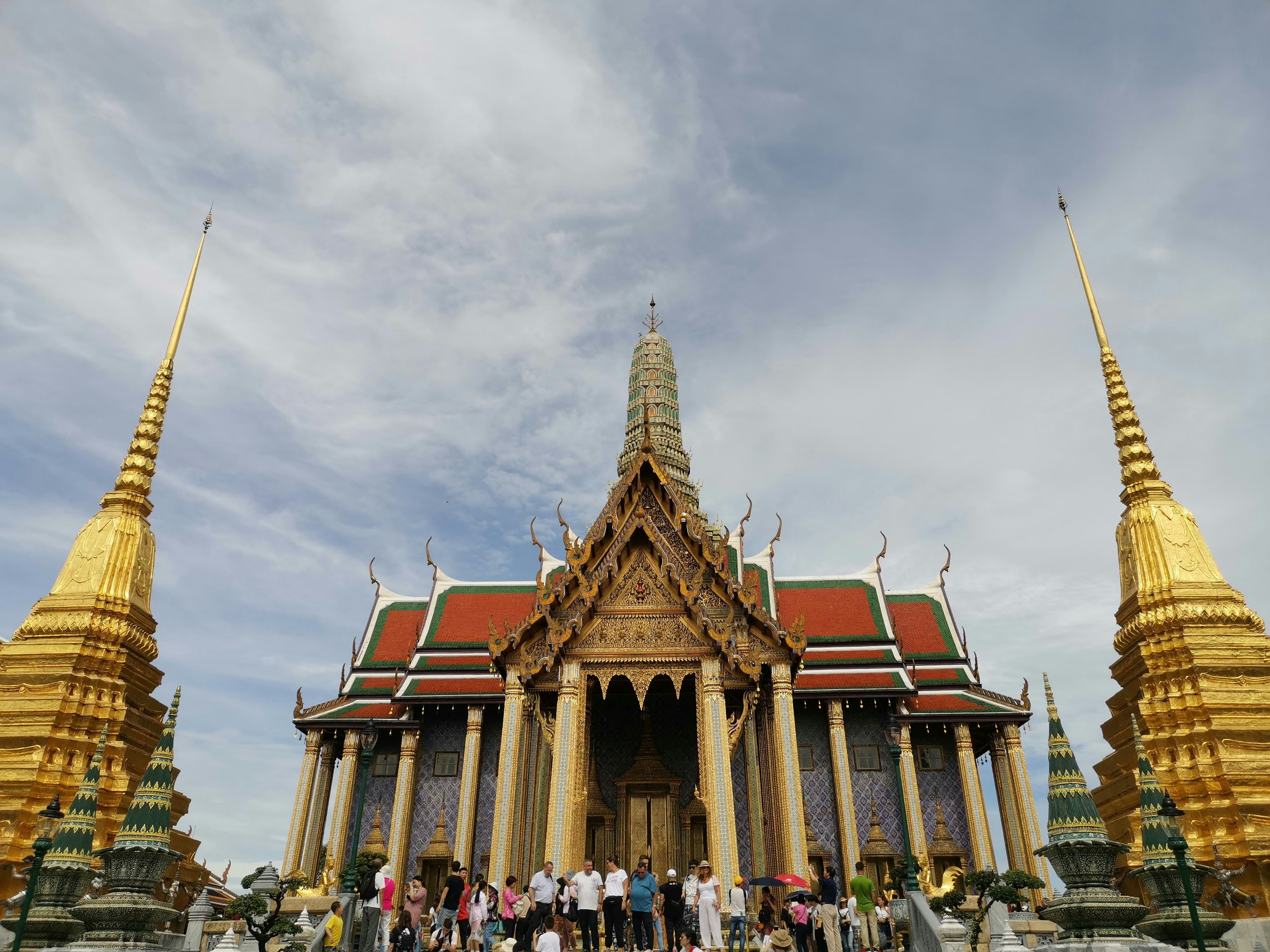 昼間、茶色と緑のコンクリートの建物の近くの通りを歩く人々