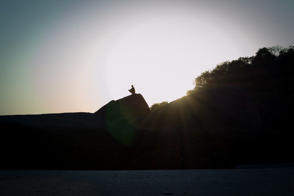 silhouette of man standing on hill during daytime