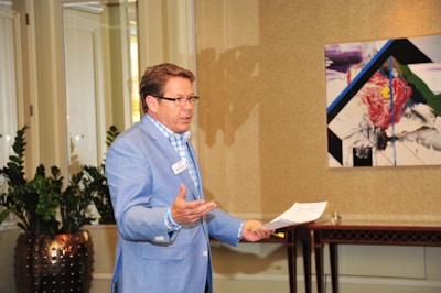 Man wearing a blue Marema GL dress shirt standing in a sunlit room.