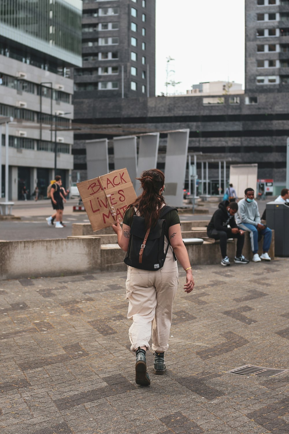 woman in black tank top and beige pants holding brown cardboard box