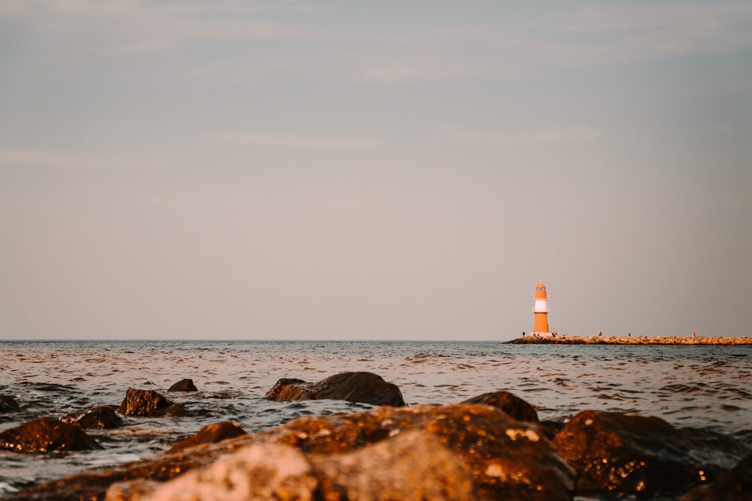 white and red lighthouse on rocky shore during daytime