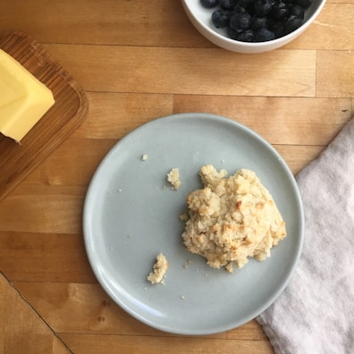 A spoon lifting a cheesy, biscuit-filled bite against a rustic wooden background.