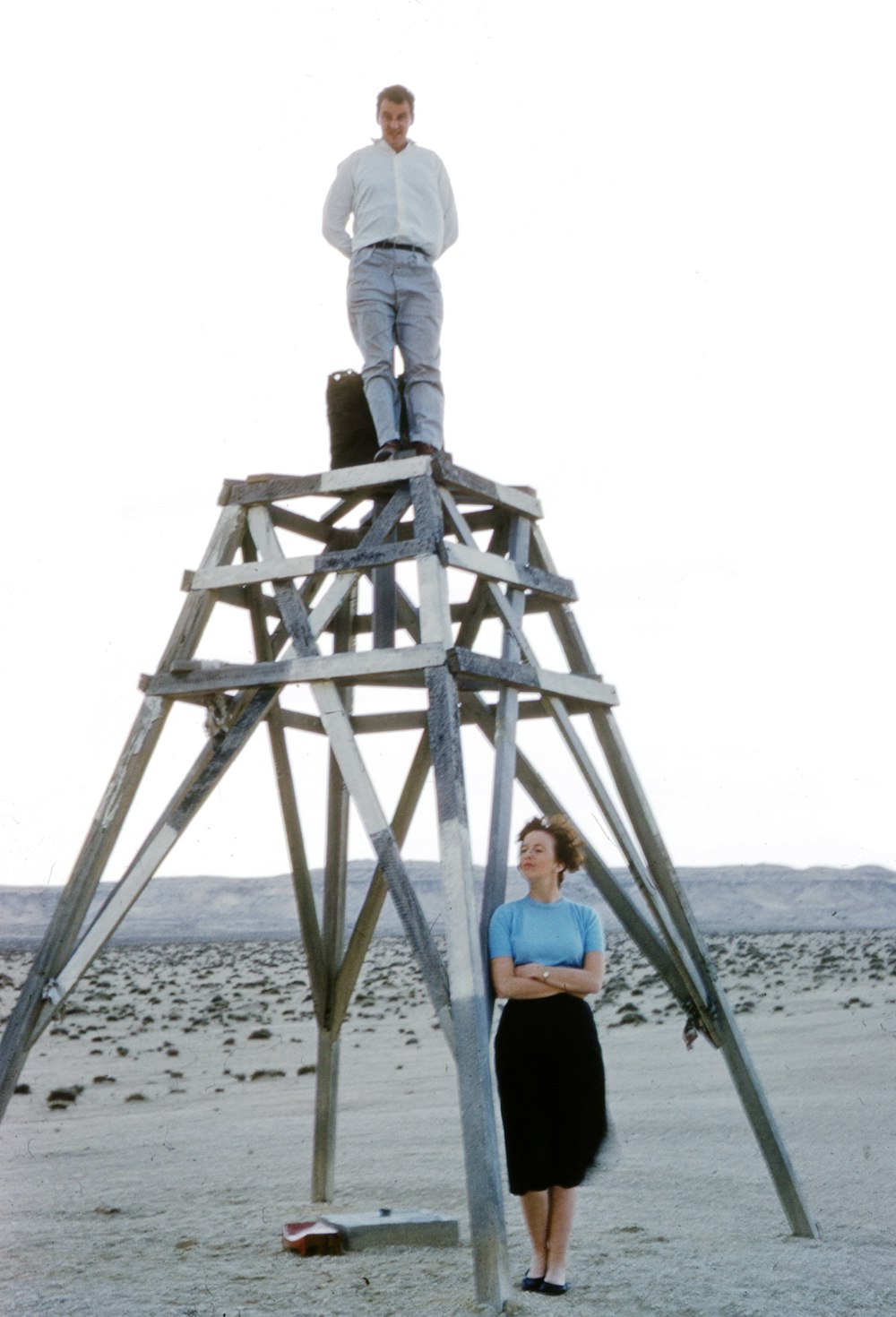 woman in blue shirt and gray pants standing on brown wooden ladder on beach during daytime