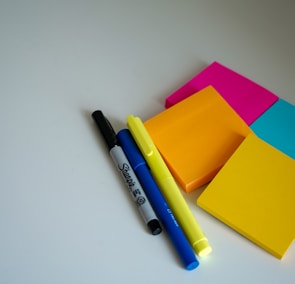 blue and black pen beside orange sticky notes