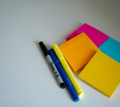 blue and black pen beside orange sticky notes