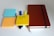 A collection of office supplies is arranged neatly, including colorful sticky notes in blue, orange, and yellow. The yellow note has 'UX Tools' written on it. There are various colorful markers and a thick brown notebook with an elastic band placed to the right.