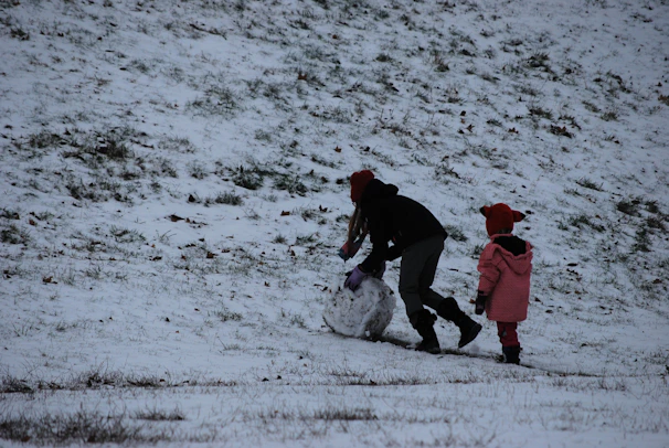 Cozy family building a snowman together in a snowy backyard.